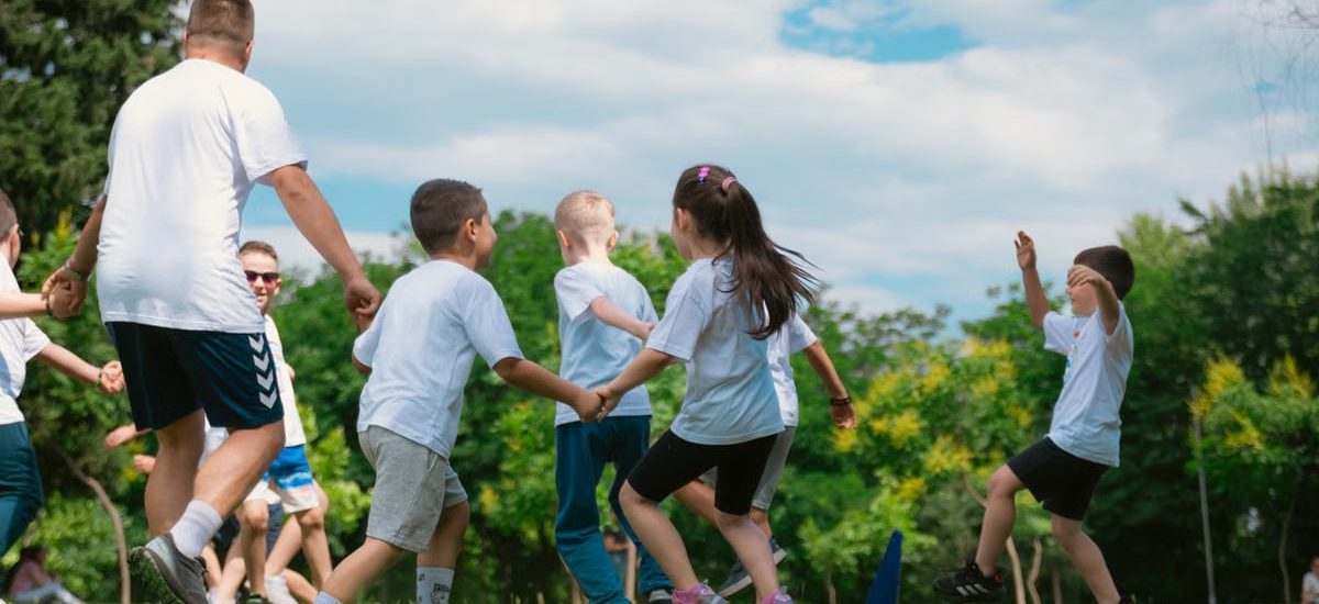 Group of children having fun and playing games together in a sunny park.