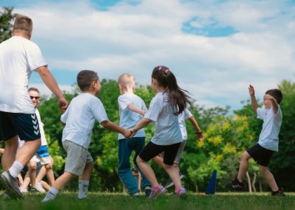 Group of children having fun and playing games together in a sunny park.